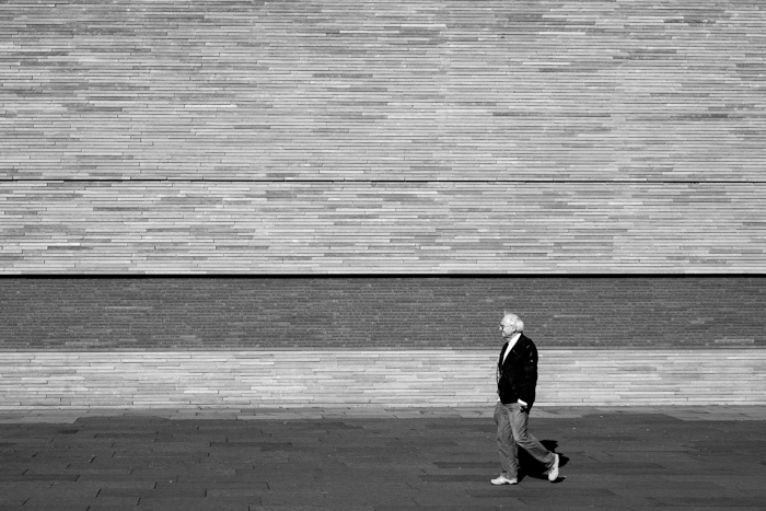 A man walks past a wall.